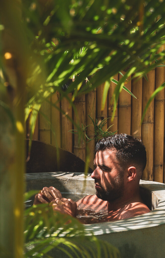 A man sat in an ice bath surrounded by palms